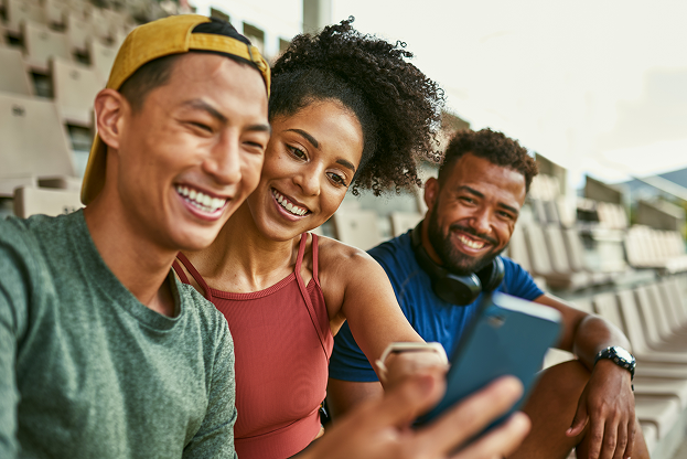 Two men and a women smiling and looking at a phone